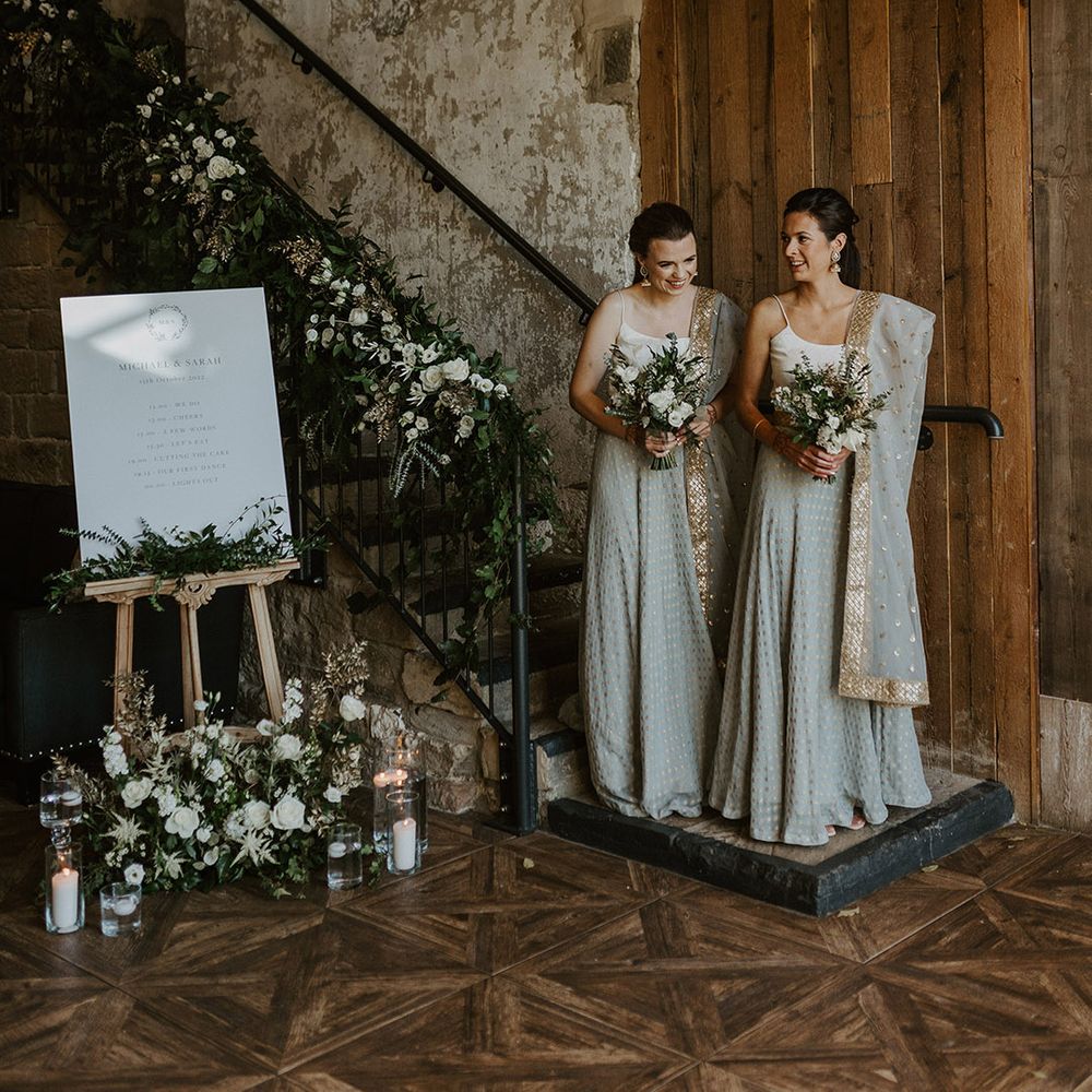 Bridesmaids in grey and gold saris for multicultural Indian English wedding next to minimalist wedding welcome sign 