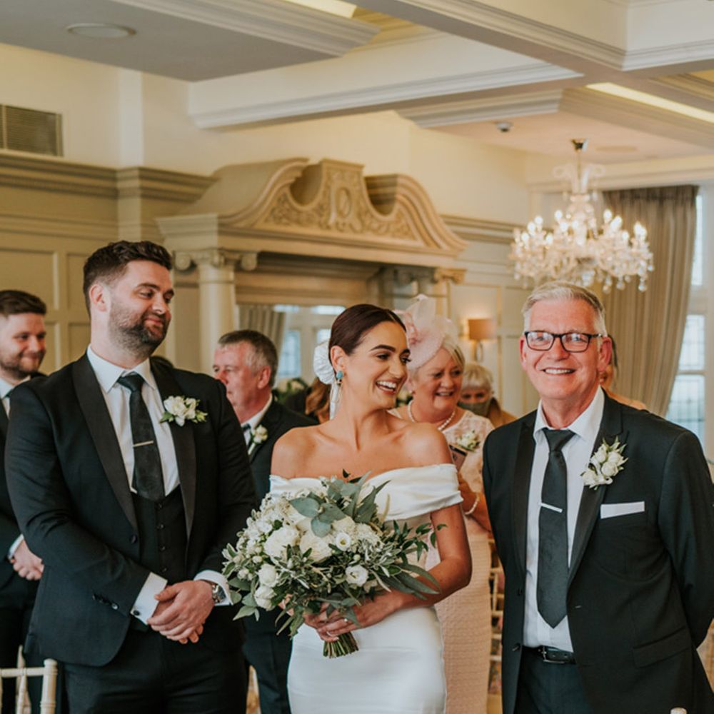 Father of the bride walks the bride to the groom at the altar for their wedding ceremony at hotel wedding venue in Northern Ireland 