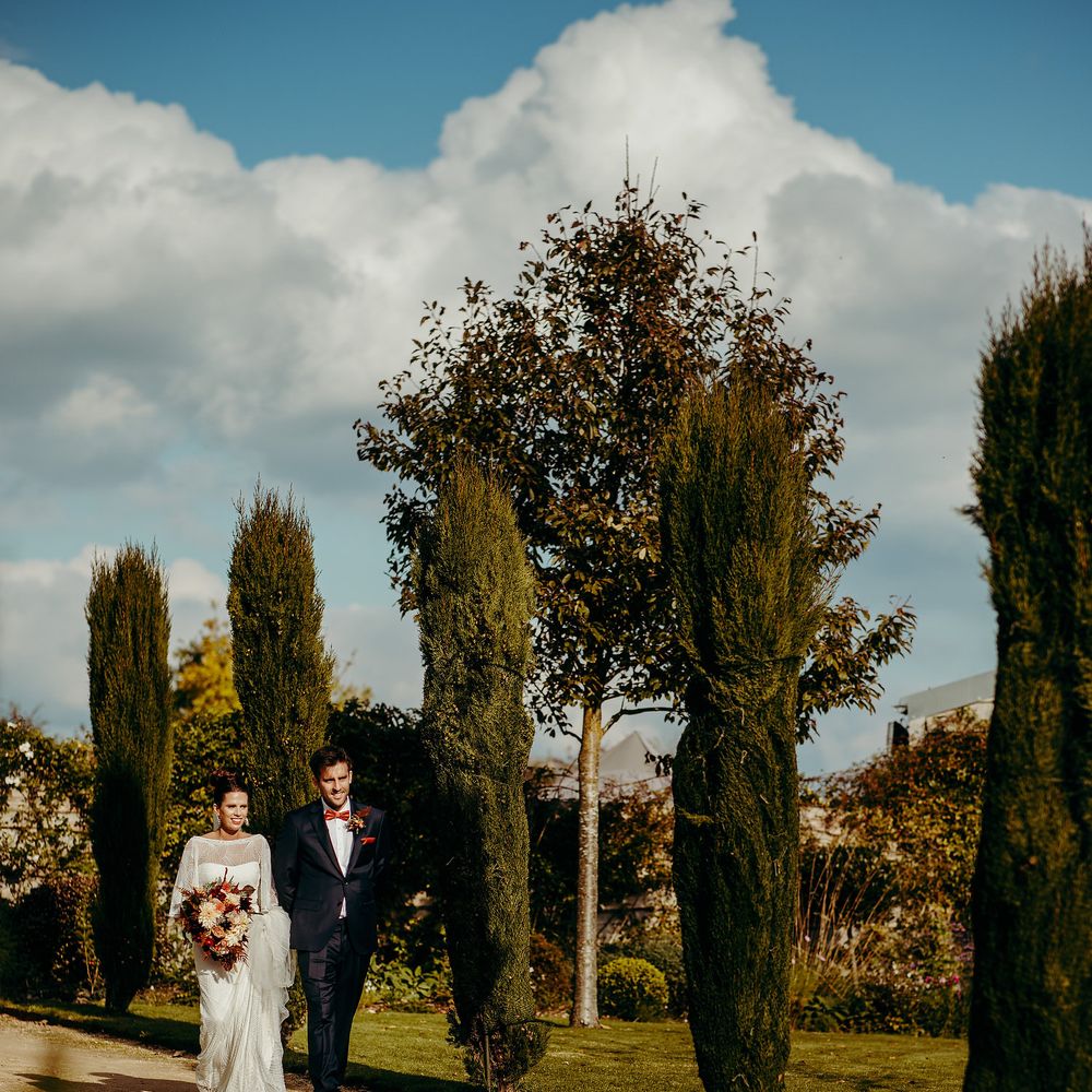 Bride & groom walk through grounds in the sunshine