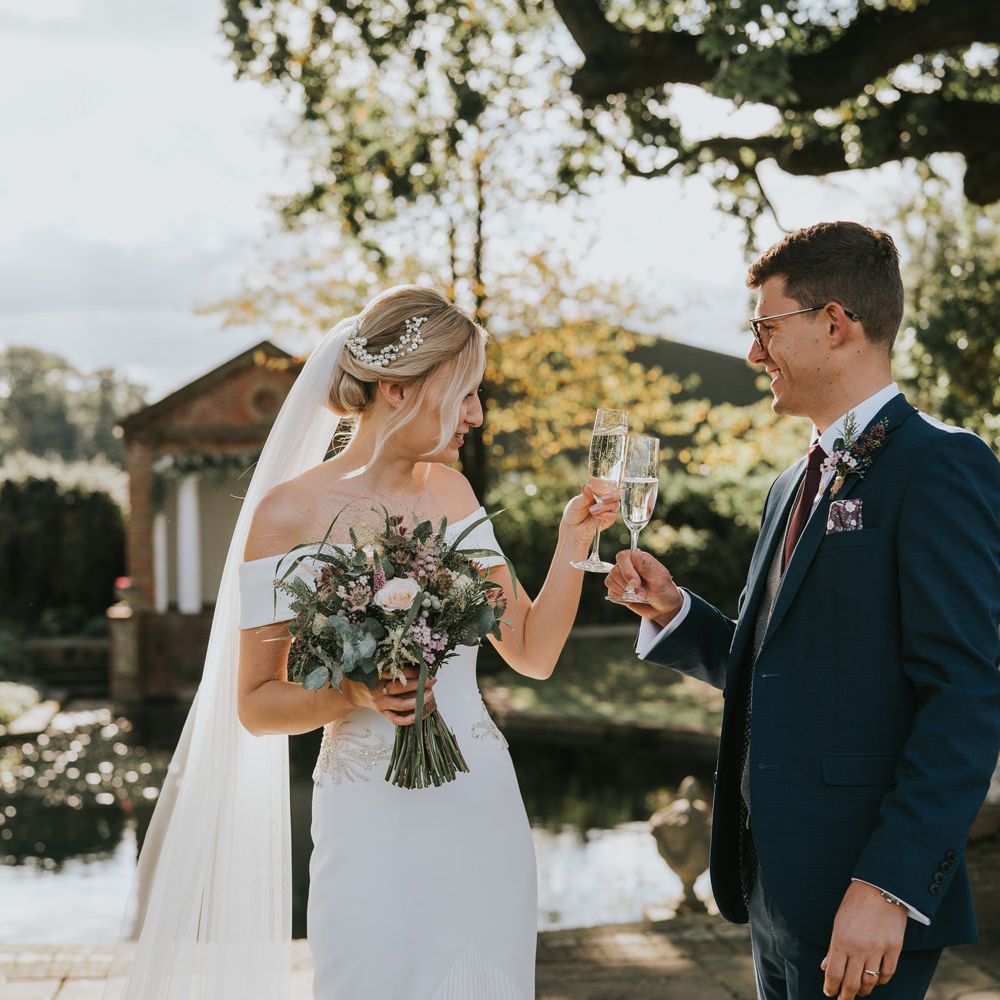 Bride & groom cheers outdoors with glasses of champagne 
