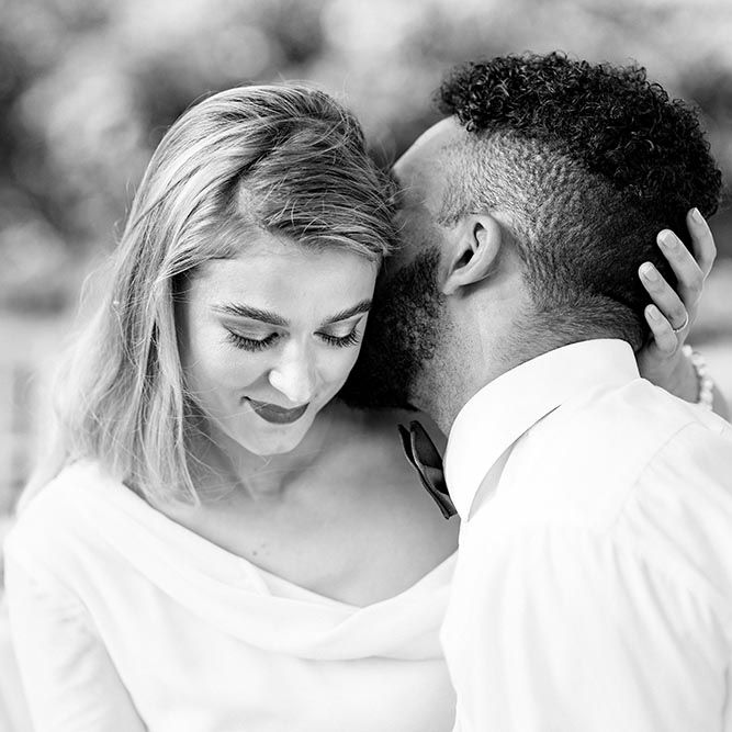 Black and white intimate bride and groom portrait with the groom kissing his brides neck 