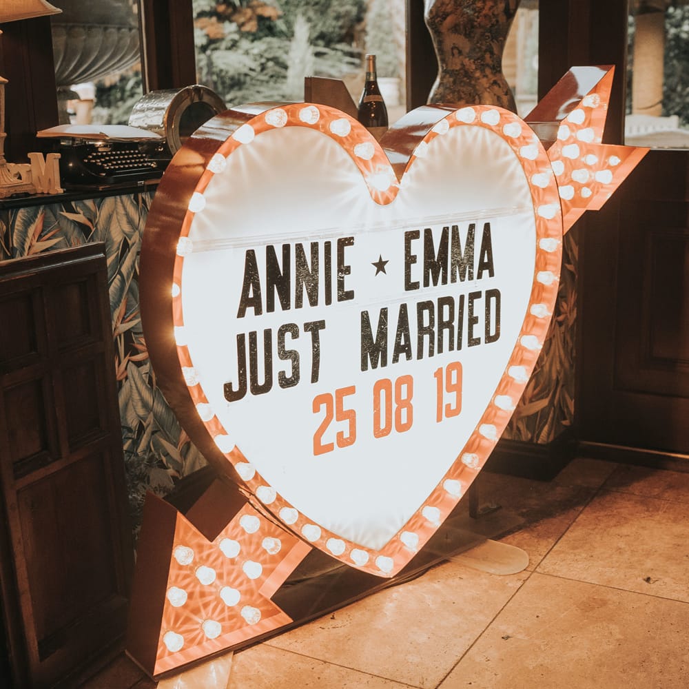 A heart shaped light box reads 'Annie and Emma Just Married 25.08.19'