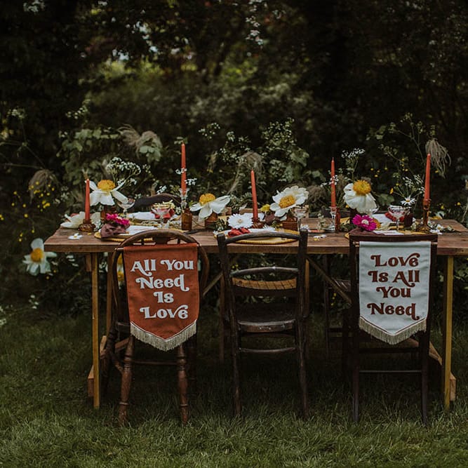 Outdoor wedding reception with fabric chair back signs, wild flowers and colourful decor 