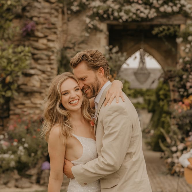intimate bride and groom portrait as they laugh and dance at their outdoor wedding with the musician playing guitar and singing in the background 
