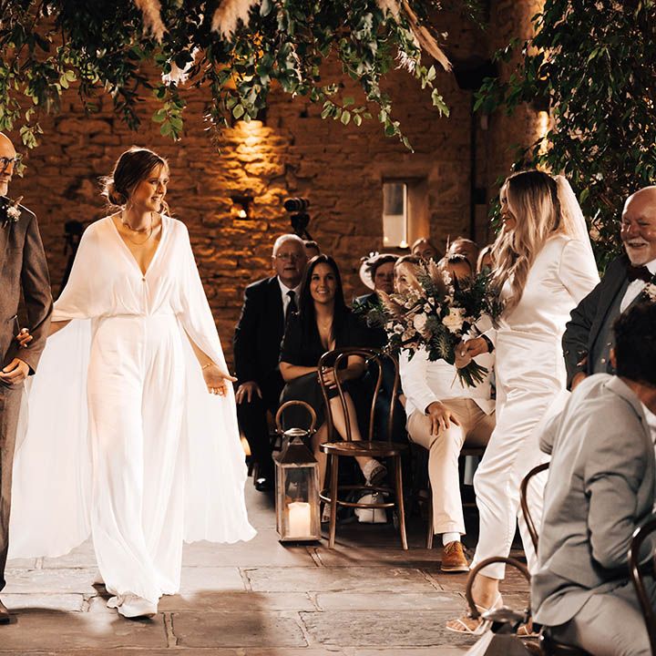 Brides meet one another midway through the aisle with their fathers to continue walking down together