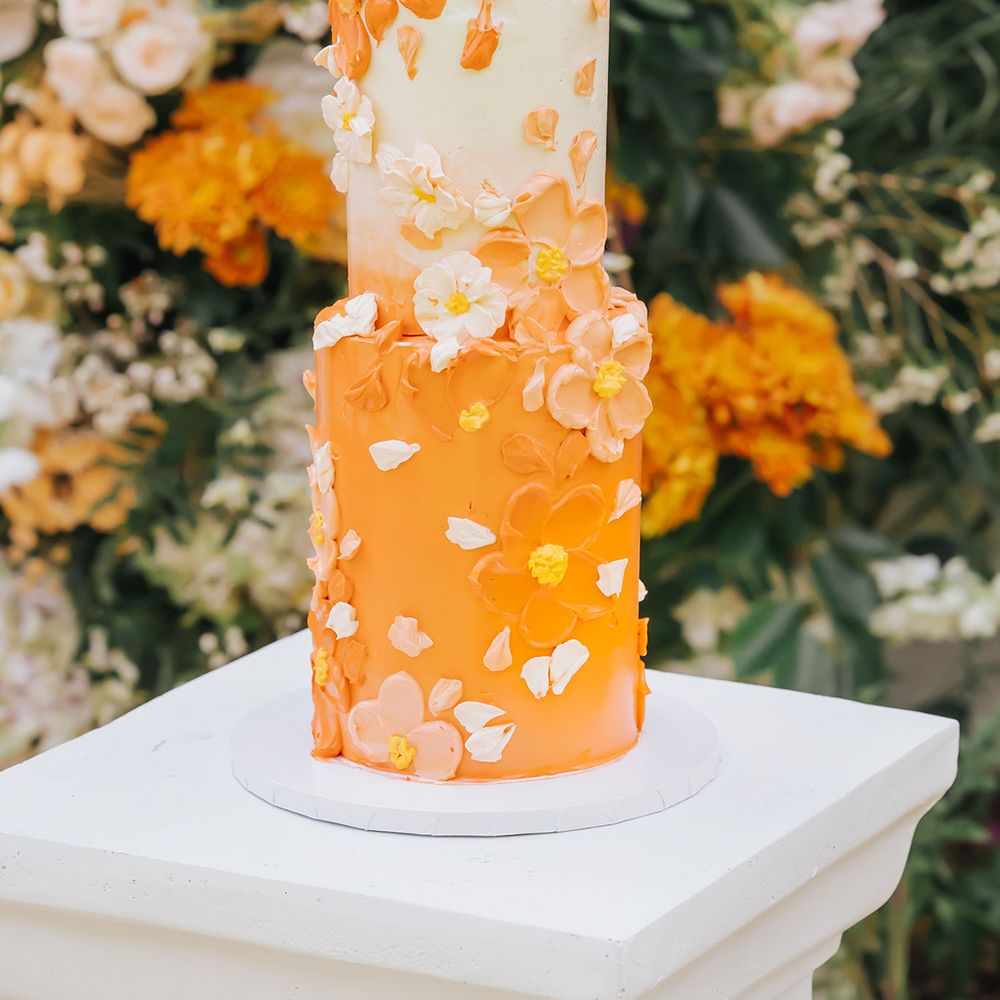 Two tier buttercream wedding cake with orange layer and petal decor 