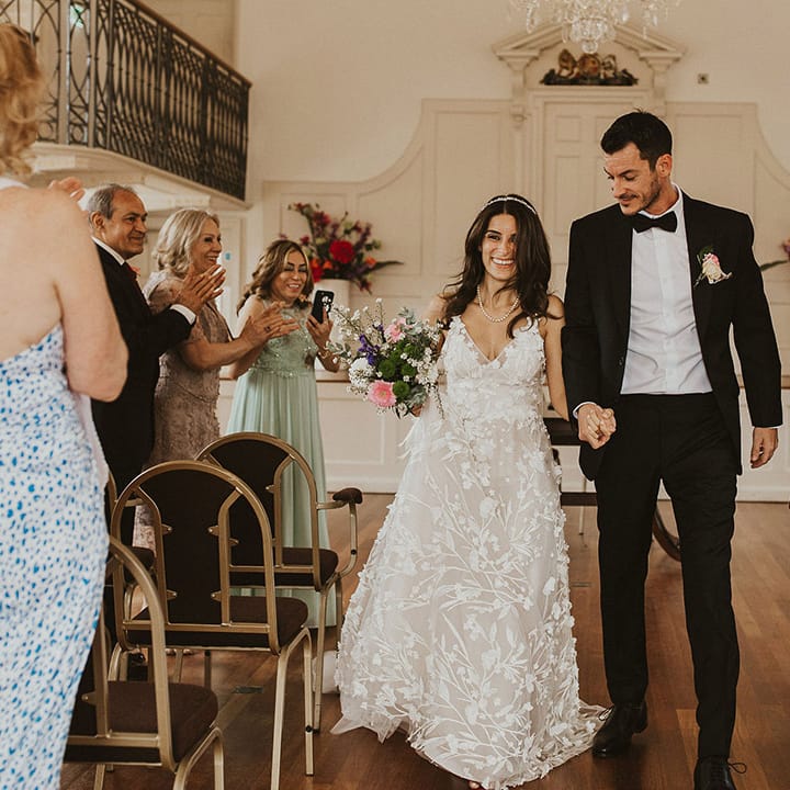 Bride & groom leave wedding ceremony as wedding guests clap