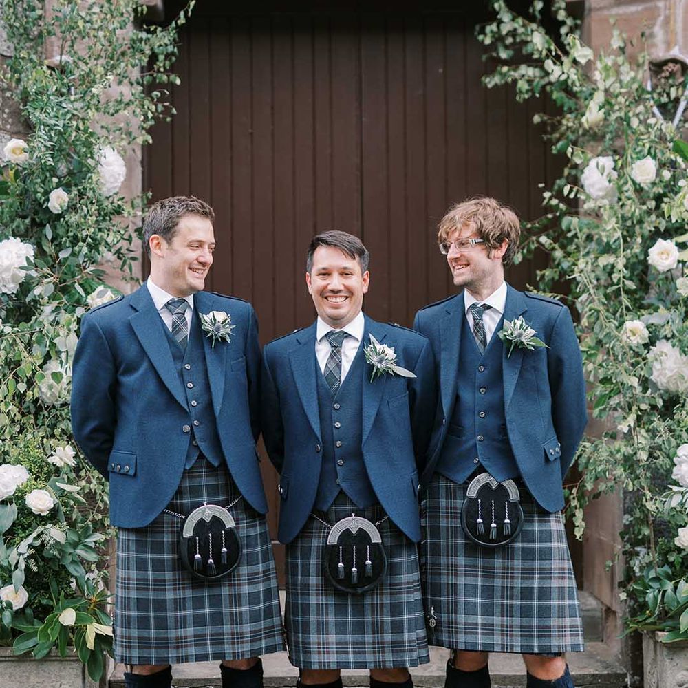 Groom and groomsmen in blue tartan kilts, sporrans and wool jackets at classic Castle wedding 