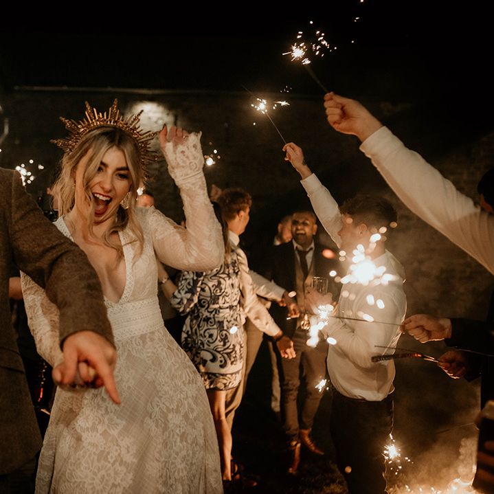 Fun sparkler moment at Lyde Court with groom in a wool suit and bride in a lace wedding dress and gown crown 