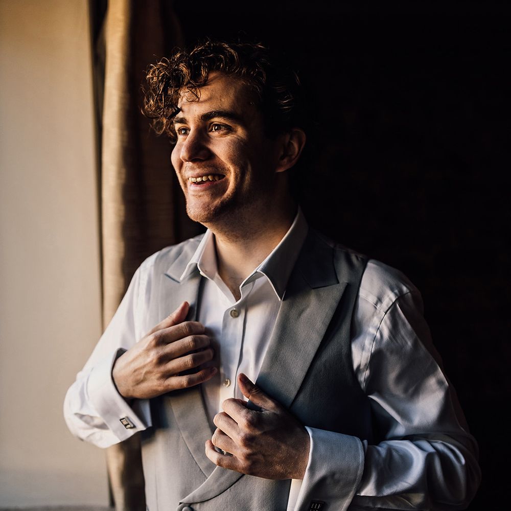 Groom in grey waistcoat gets ready for wedding at Oxnead Hall