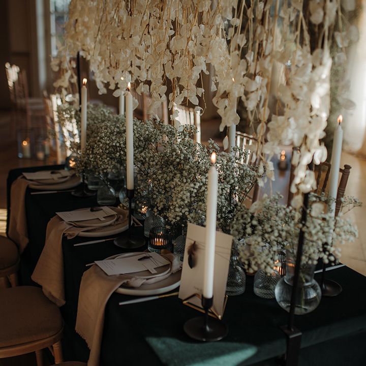 Luxury tablescape at Hodsock Prory with hanging flower installaion and gypsophila centrepiece flowers on a black table cloth 