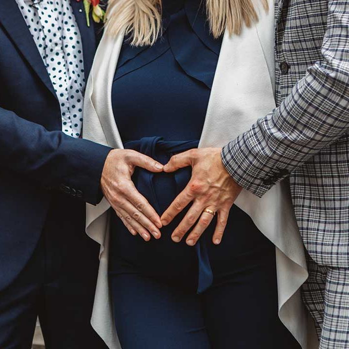 Grooms make a heart shape around their surrogates belly 
