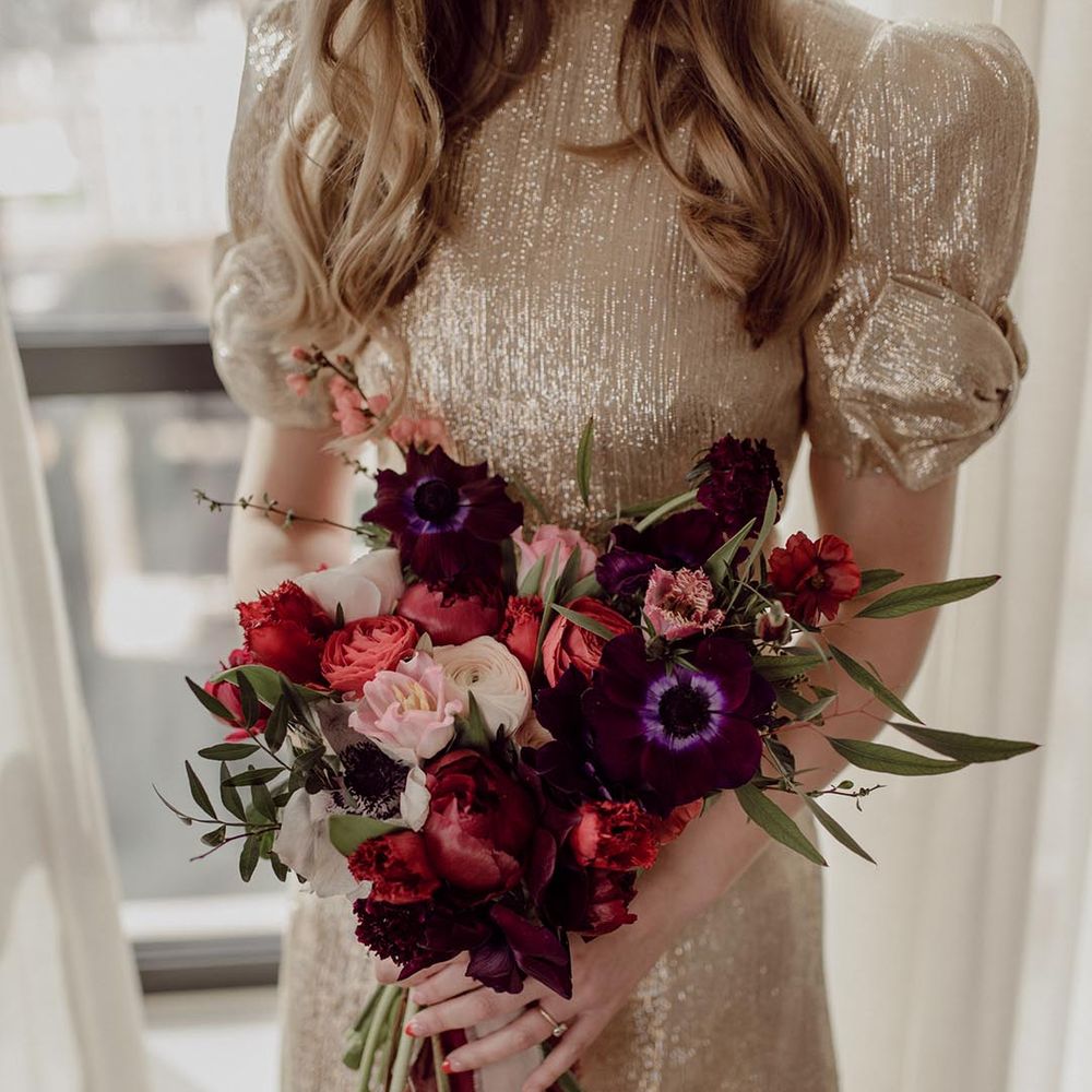 Bride in sparkly wedding dress holding pink, red and purple flower wedding bouquet