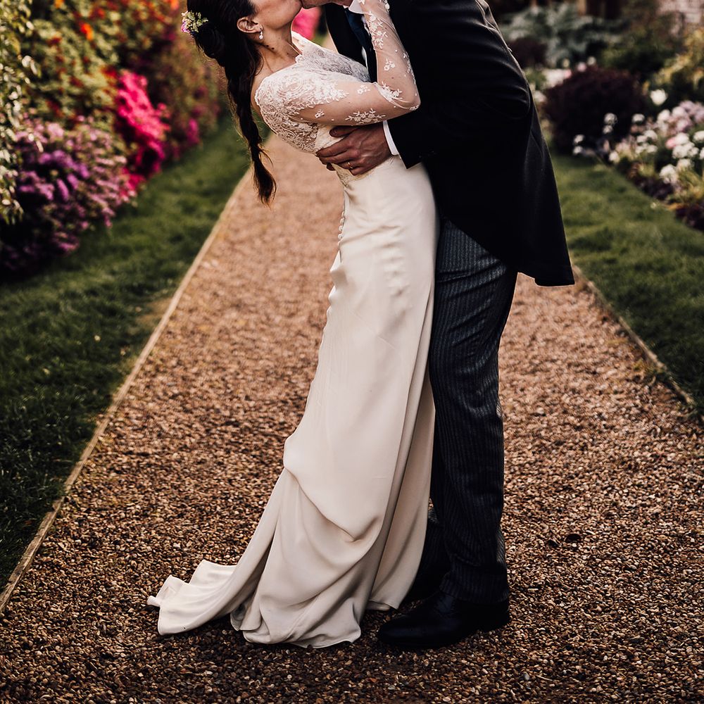 Bride leans back as the groom kisses her in the gardens of Wadhurst Castle wedding venue 