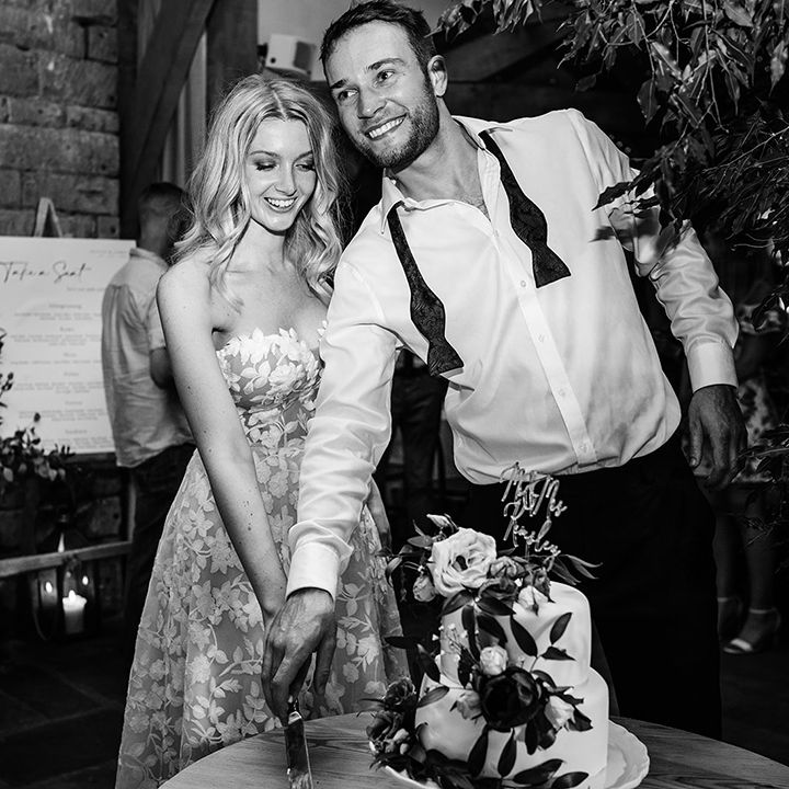Bride and groom cut their two tier wedding cake with personalised cake topper 