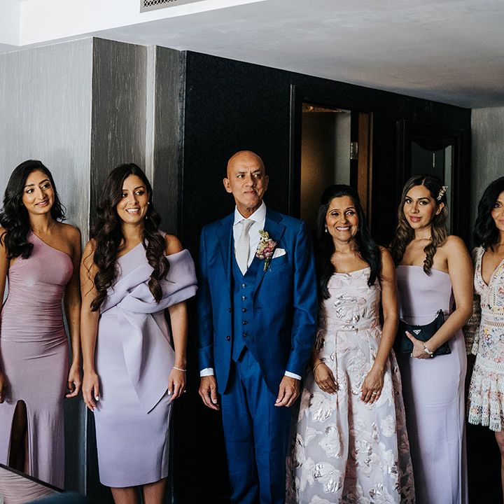 Bridesmaids wearing lavender bridesmaid dresses stand with brides family on the morning of wedding day at Syon Park