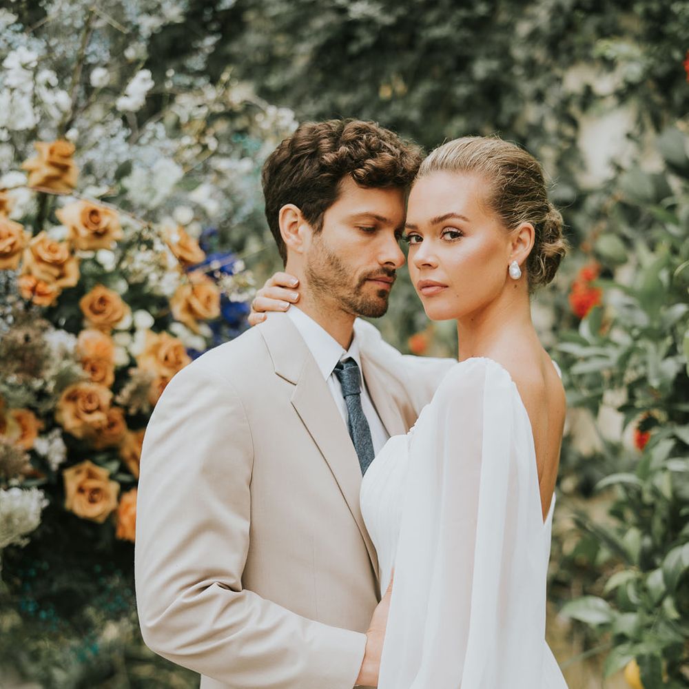 Groom wears a beige suit with the bride in a sheer balloon sleeve wedding dress