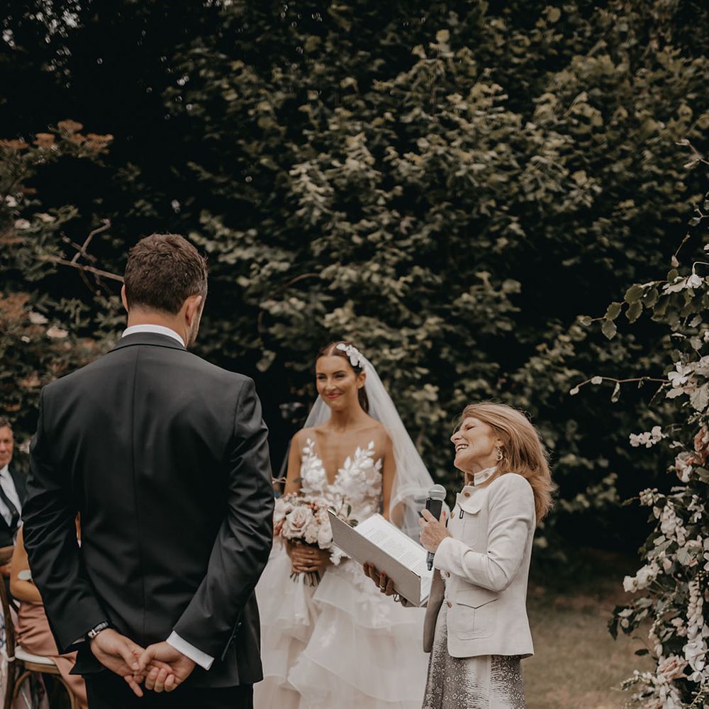 Bride and groom stand smiling during their outdoor wedding ceremony 