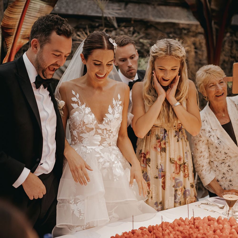 Wedding guests smile with the bride and groom over the wedding dessert 