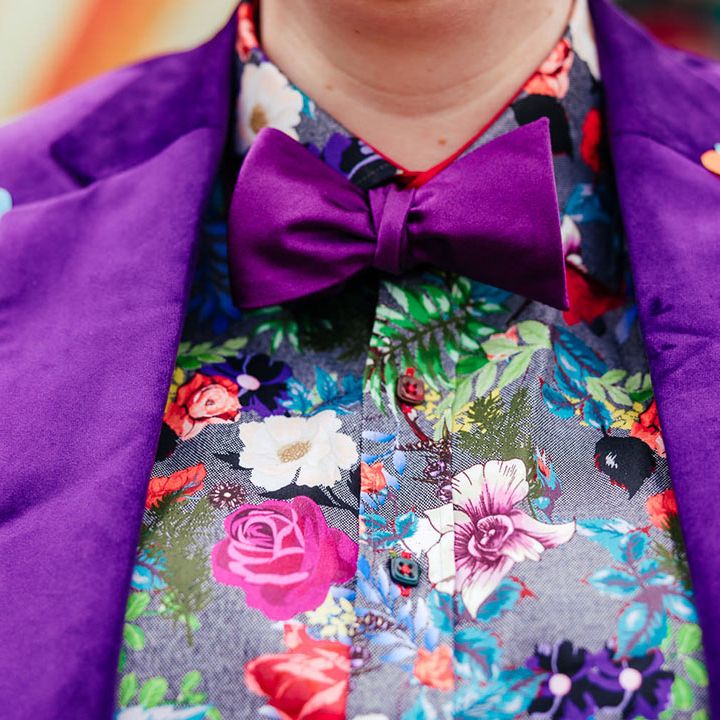 Bride in purple velvet blazer with purple bowtie, pink patterned pocket square and colourful patterned shirt 