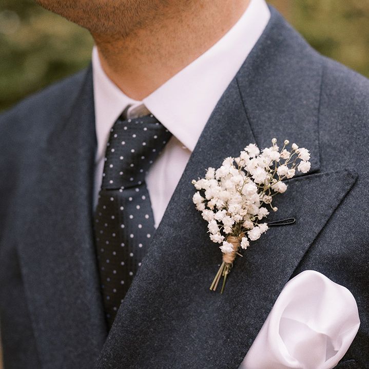 Groom in dark navy suit with matching tie with spots and white gypsophila buttonhole with white pocket square 