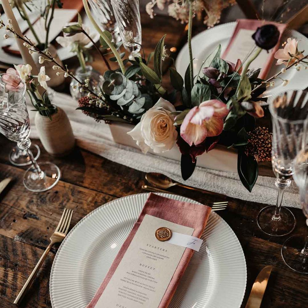 Dusky pink cotton napkin on minimalistic wedding menu with gold cutlery and rose, carnation, eucalyptus, dried flower and baby's breath floral arrangements 