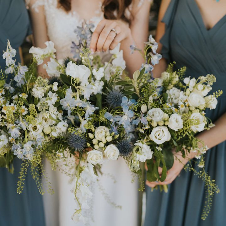 The bride and bridesmaids hold matching blue and white wedding bouquets with daisies for the rustic theme wedding at Badgers Holt 