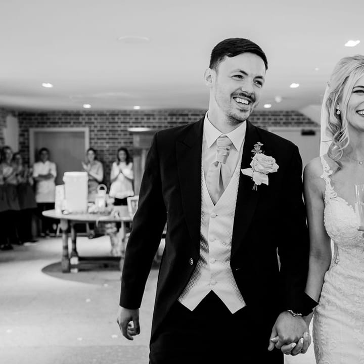 The bride and groom walk into their wedding reception together at Rackleys Chiltern Hills barn wedding venue 