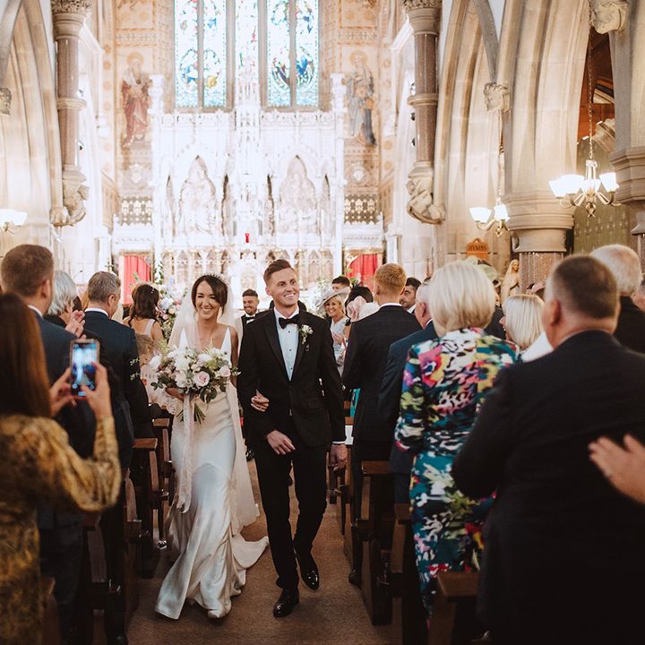 The bride and groom walk back down the aisle at their church wedding 