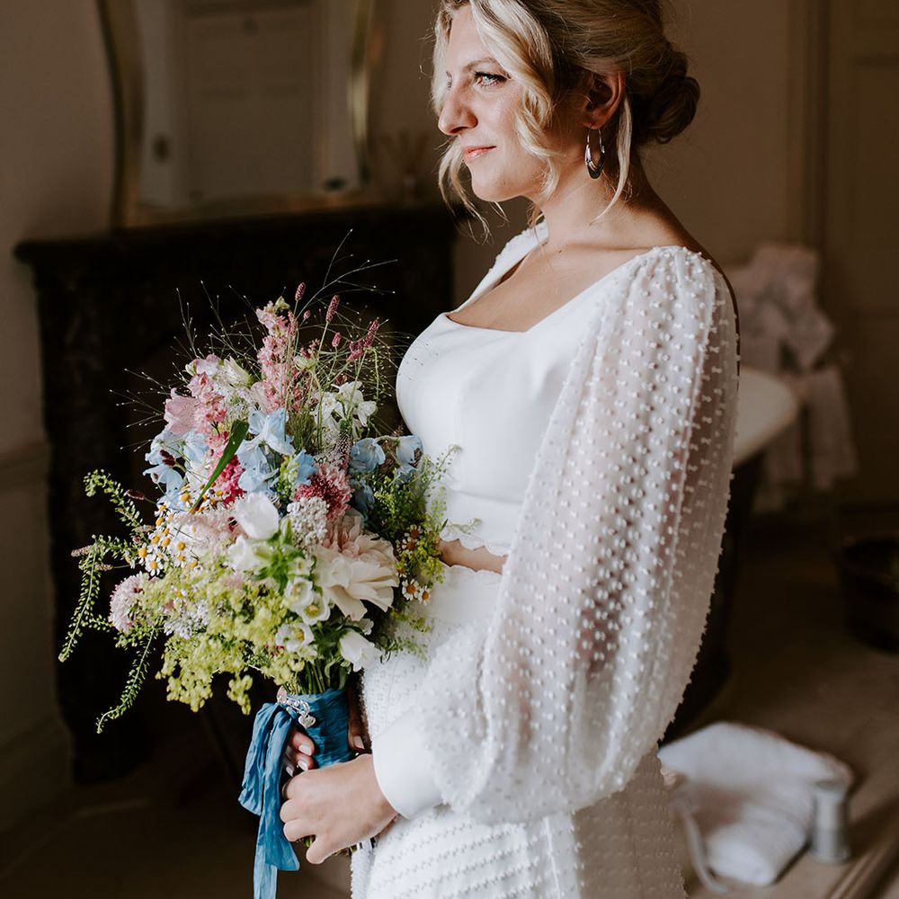 Bride in spotted long sleeve bridal top and skirt separates holding pastel wildflower wedding bouquet 