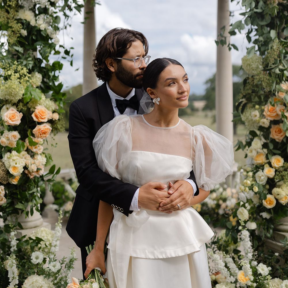 groom--in-black-tux-embraces-bride-surrounded-by-yellow-wedding-flowers