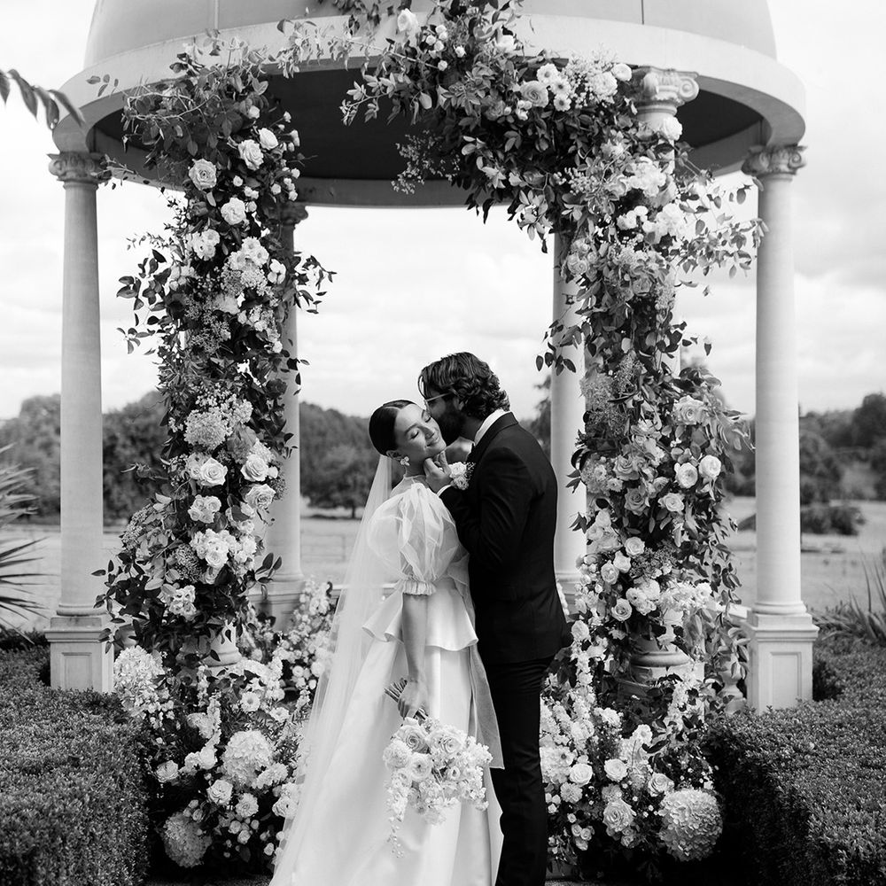 outdoor-wedding-ceremony-as-the-bride-gets-kissed-on-the-cheek-by-the-groom