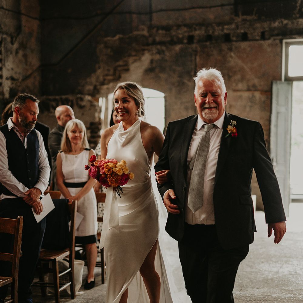 father-of-the-bride-walks-bride-in-satin-wedding-dress-down-the-aisle