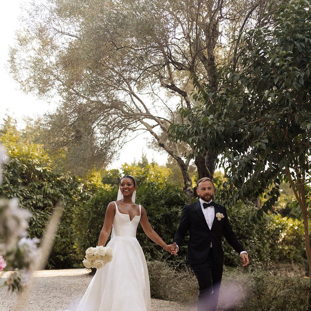 bride-and-groom-walking-hand-in-hand-wearing-black-tuxedo