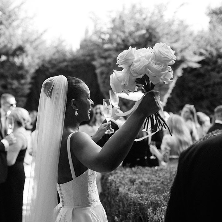 bride-holds-white-rose-bouquet-in-the-air