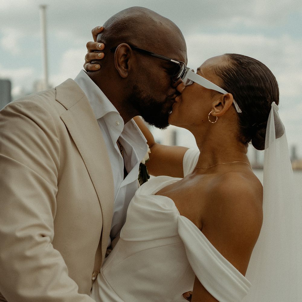groom-in-cream-suit-kissing-bride-in-off-the-shoulder-wedding-dress