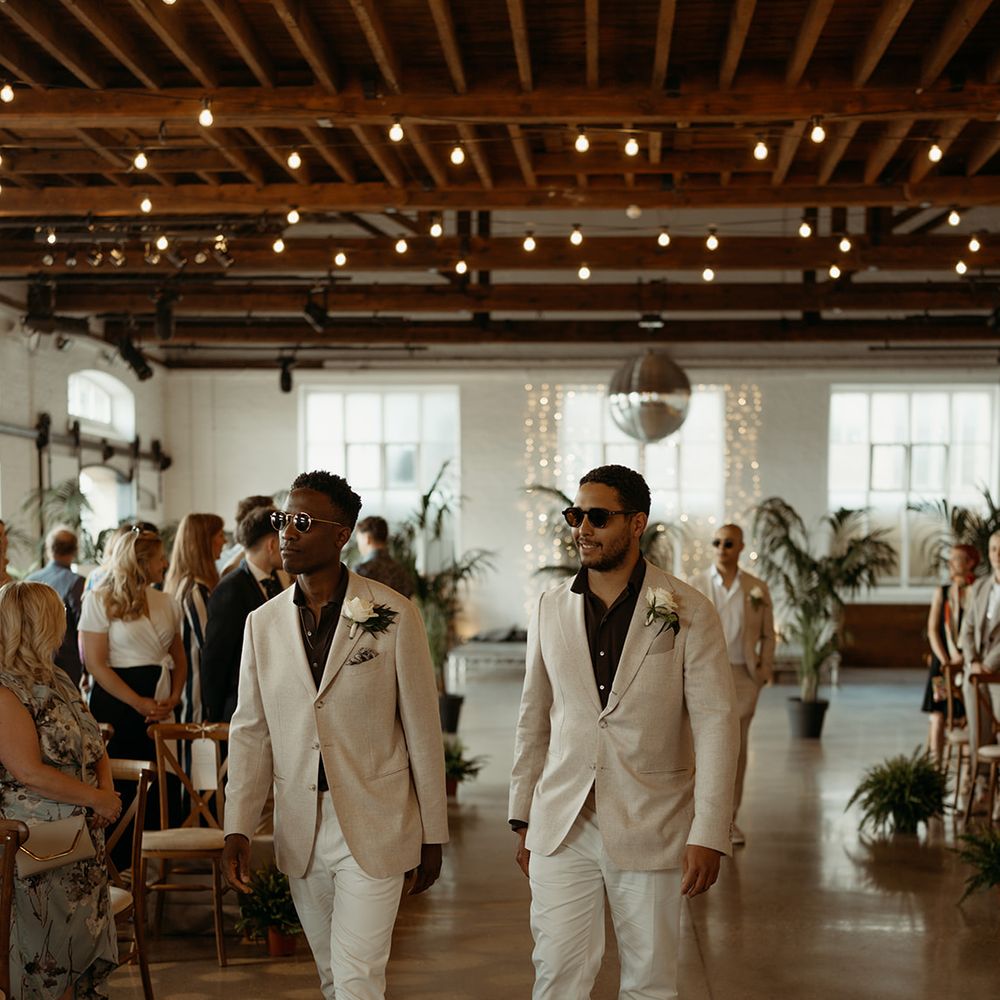 groomsmen-walk-down-the-aisle-wearing-black-shirts-and-cream-suit-jackets