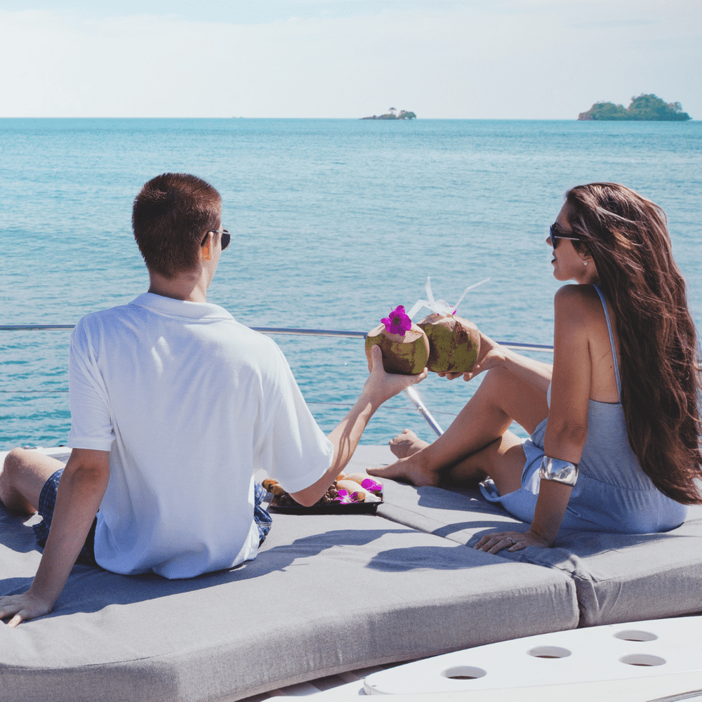 Couple enjoying coconut drinks together on a boat trip during their honeymoon.
