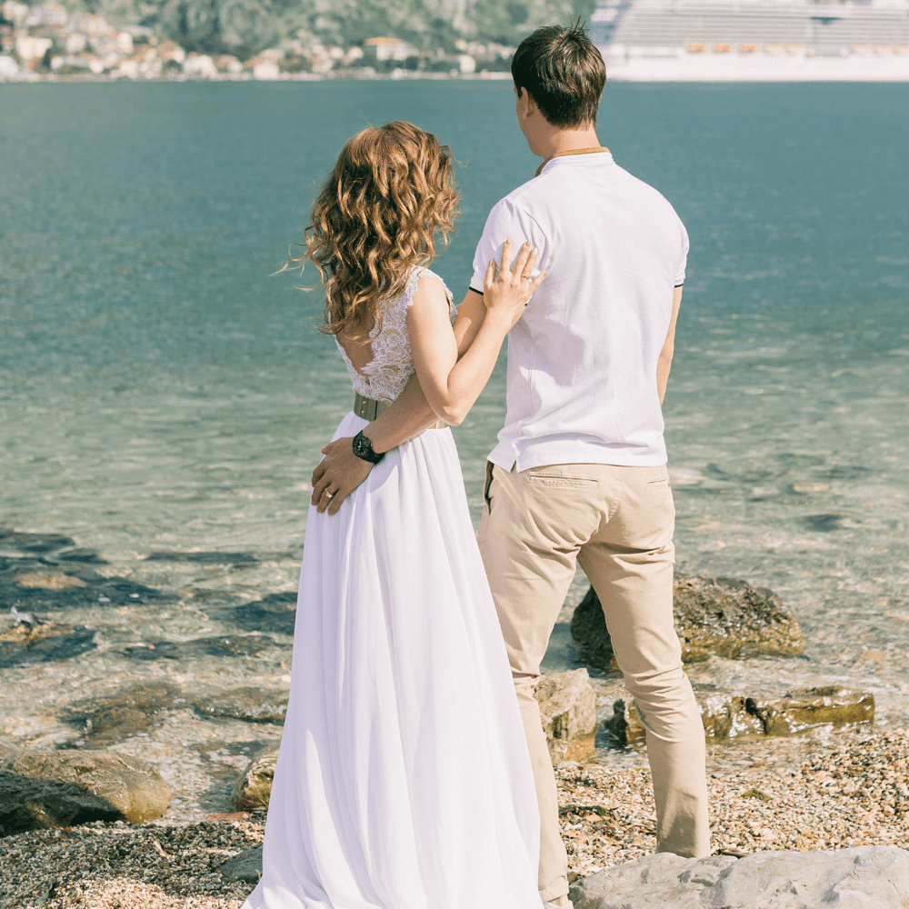 Couple embracing each other while gazing at a mountain and sea view during their honeymoon.
