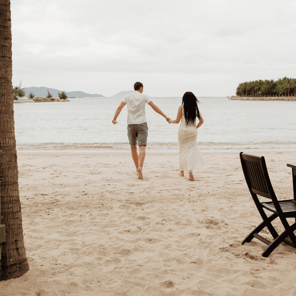 couple joyfully running along the beach towards the sea, celebrating their honeymoon