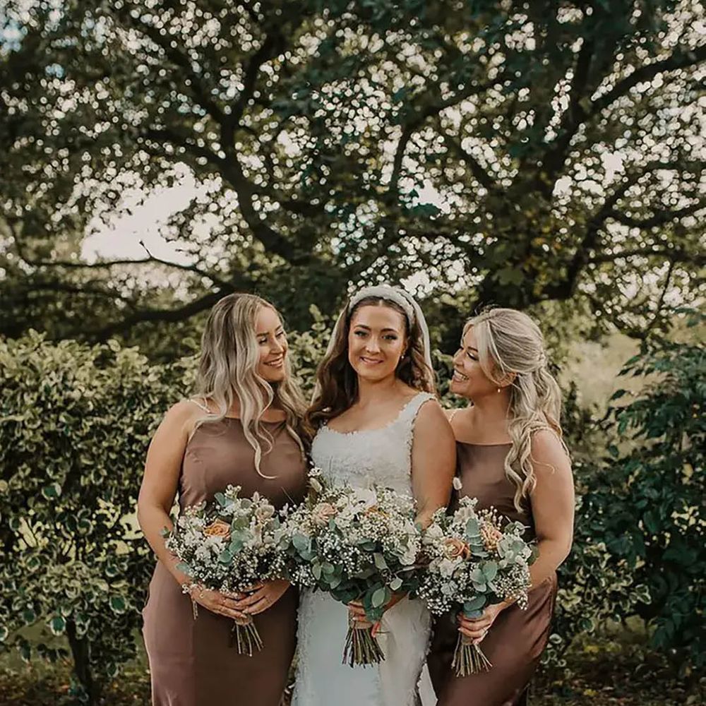 bride with two of her bridesmaids wearing brown satin dresses