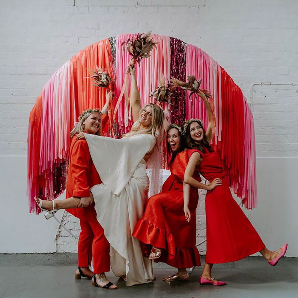 bridesmaids wearing bright red dresses while posing with bride