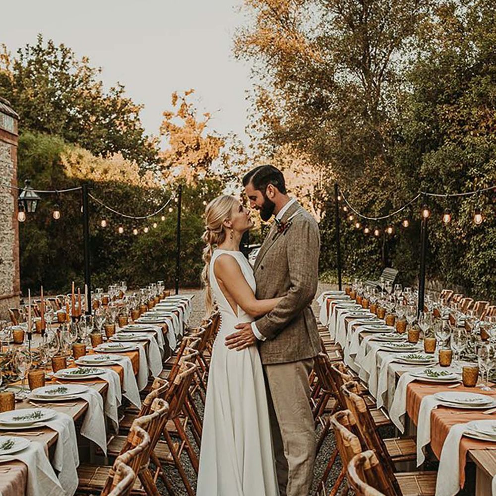 bride and groom embracing at outdoor wedding with earthy toned table decor