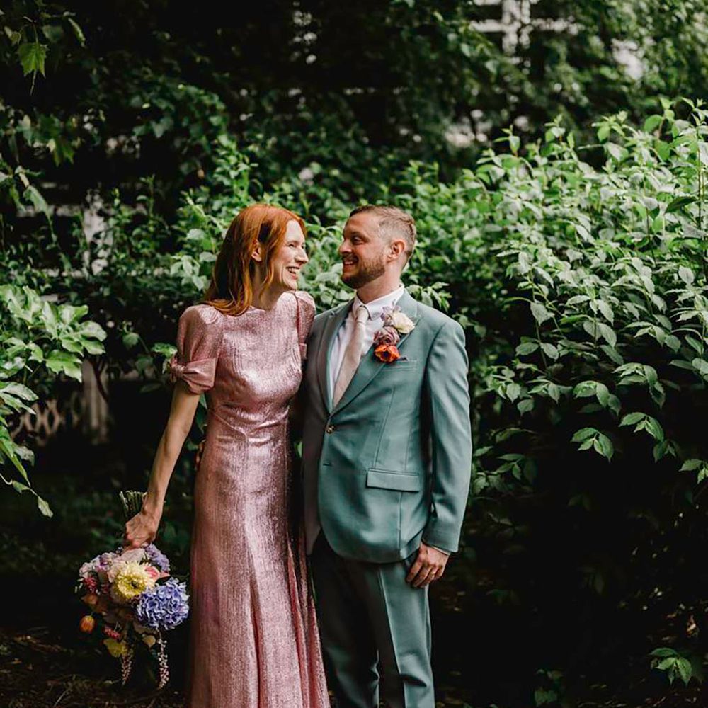 bride wearing pink metallic wedding dress and groom in green suit