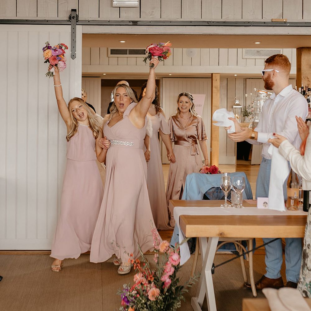 bridal-party-wearing-pink-bridesmaid-dresses-with-bouquets-enter-wedding-reception
