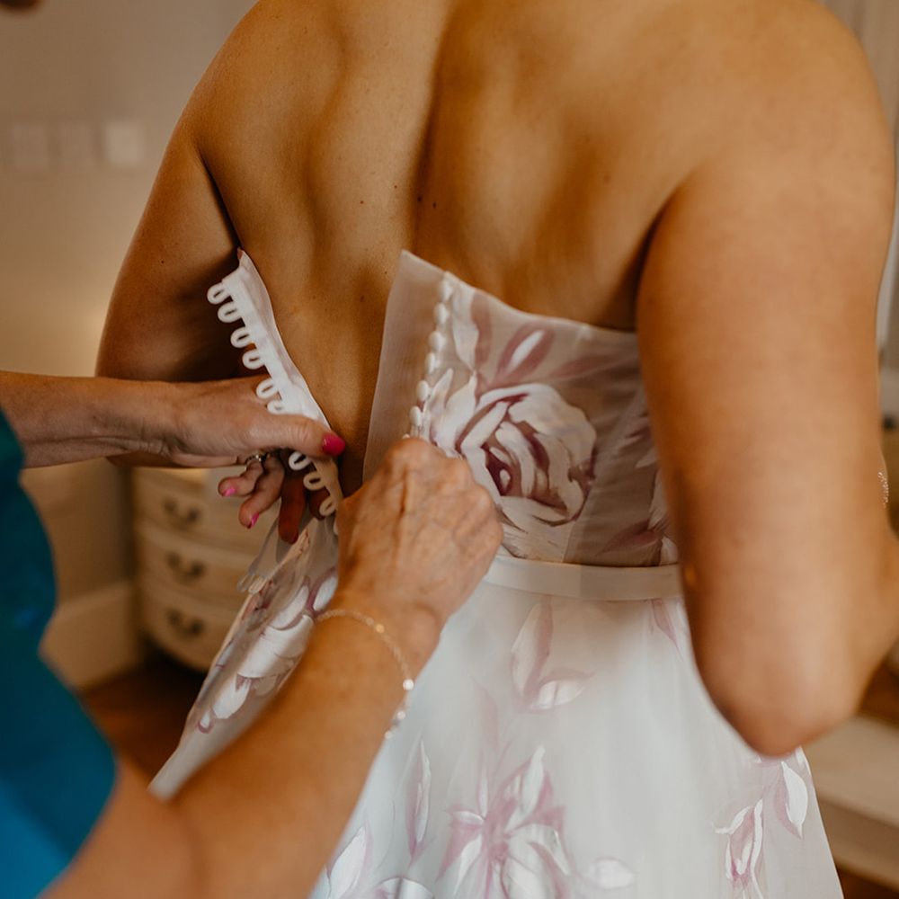 bride-gets-buttoned-into-wedding-dress