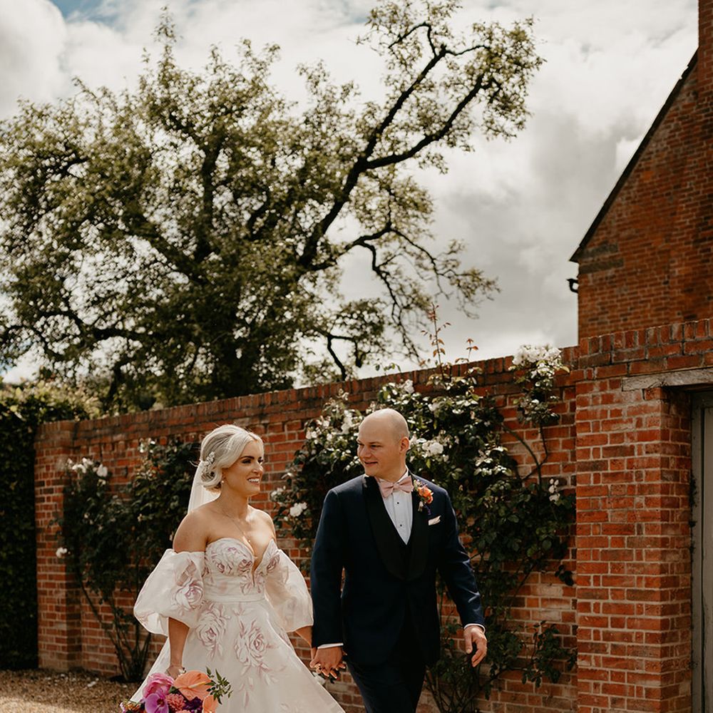bride-wearing-pink-flower-wedding-dress-with-bouquet-walking-with-groom