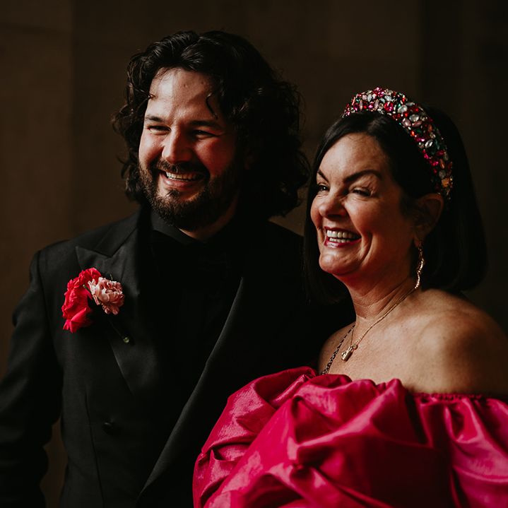 groom-smiling-with-wedding-guest-in-pink-dress-and-crown