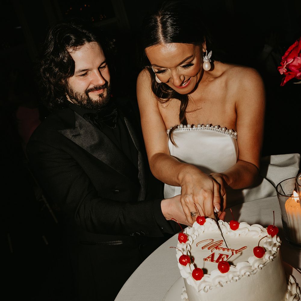 heart-shaped-wedding-cake-with-cherries-cut-by-bride-and-groom