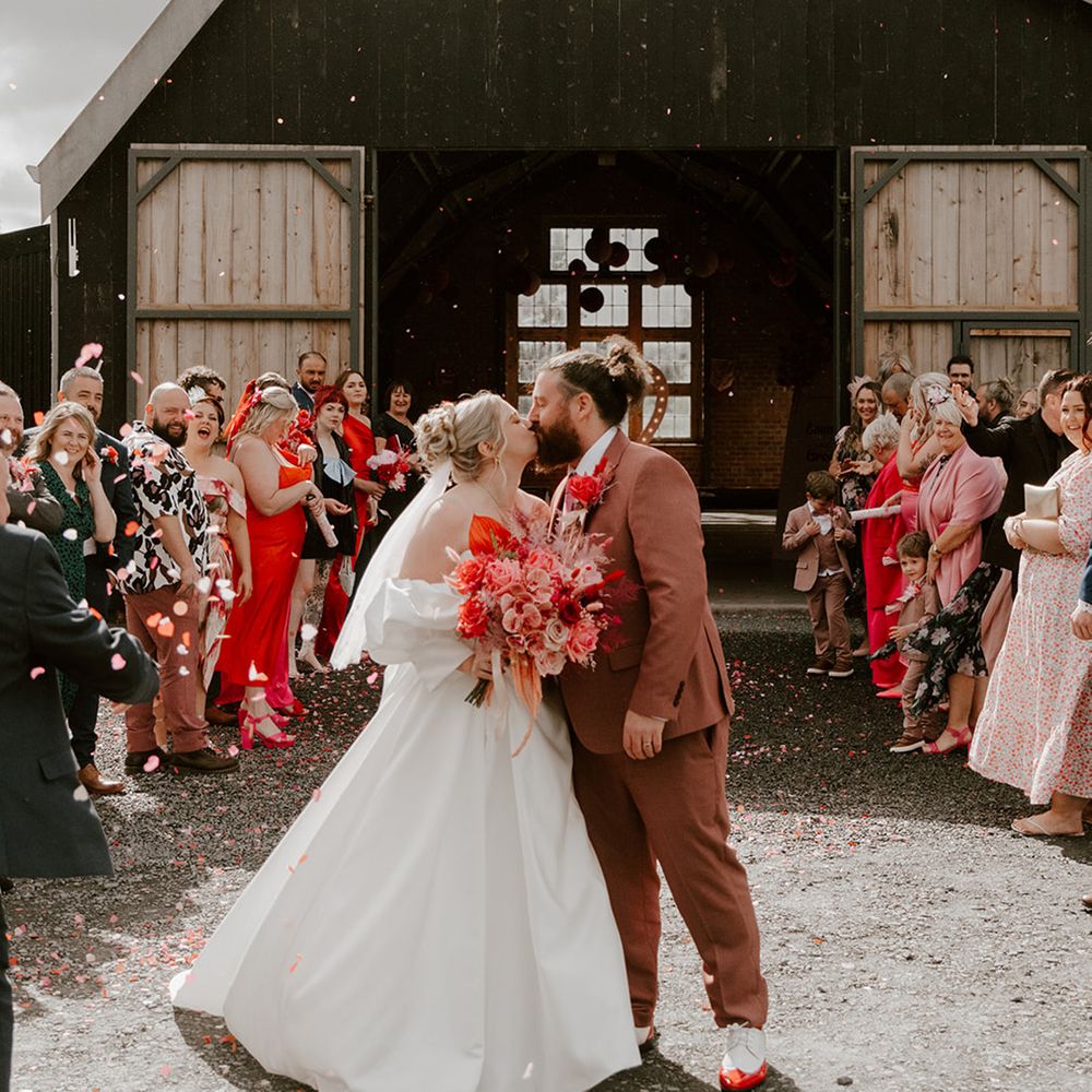 bride-in-puff-sleeve-dress-and-groom-in-pink-suit-kiss